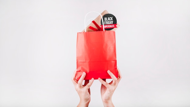 Mãos segurando saco de compras vermelho preto sexta feira