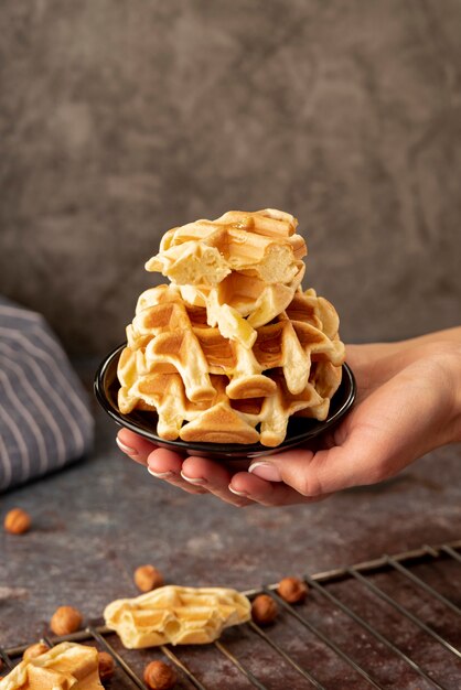 Mãos segurando um prato com pilha de waffles