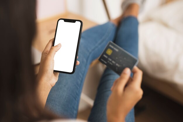 Mãos segurando um telefone e cartão simulado