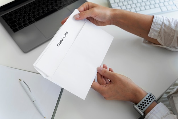 Mãos segurando uma carta de demissão de alto ângulo