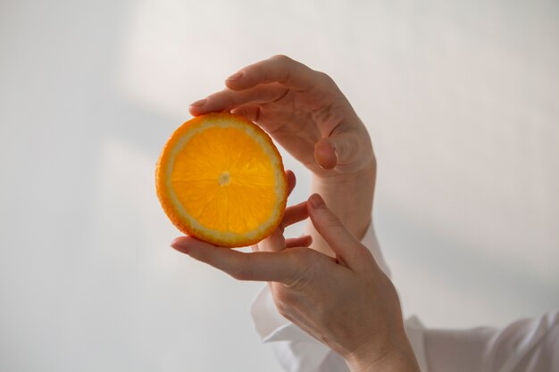 Mãos segurando uma fatia de laranja vista lateral