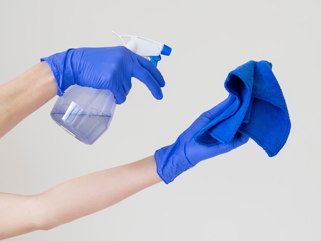 Mãos segurando uma garrafa de ablução e pano para desinfetar