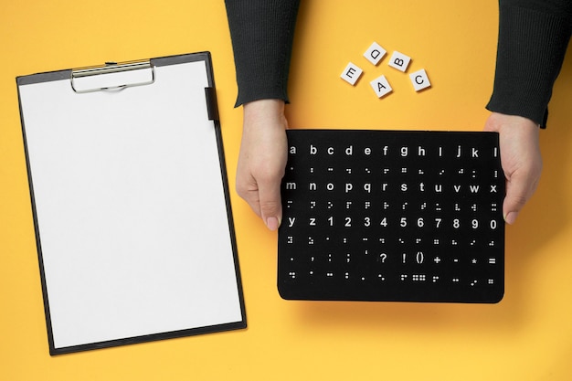 Mãos segurando uma placa do alfabeto braille