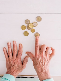 Mãos seniores contando moedas de euro na mesa
