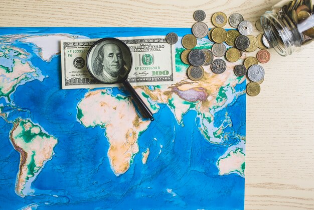 Mapa do mundo com dinheiro e lupa