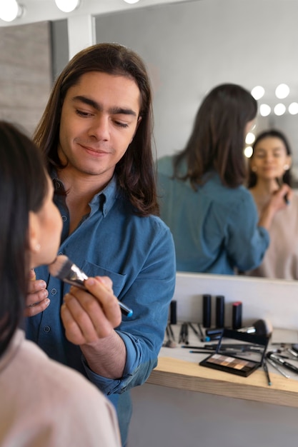 Foto grátis maquiador masculino colocando maquiagem em cliente feminina