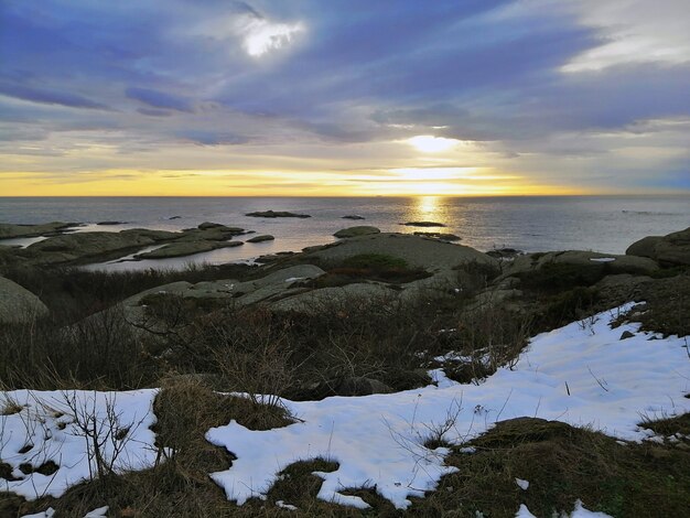 Mar cercado por rochas sob um céu nublado durante o pôr do sol em Rakke, na Noruega