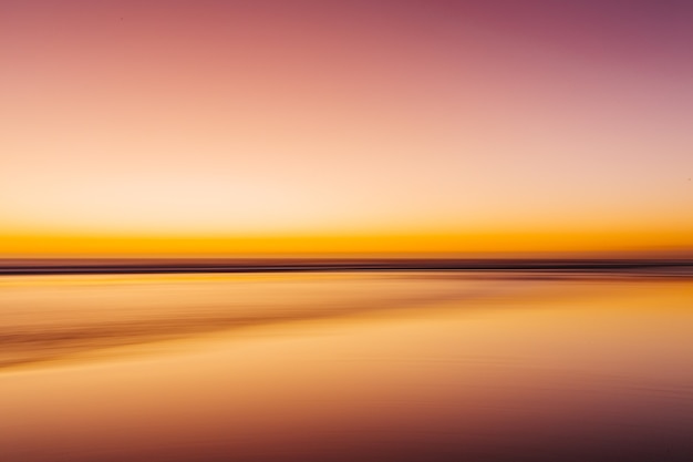 Mar durante um pôr do sol colorido com um efeito de movimento - uma imagem legal para papéis de parede e fundos