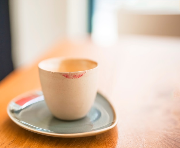 Marca de batom na xícara de café sobre a mesa de madeira