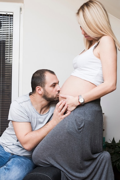 Marido beijando a barriga da mulher grávida