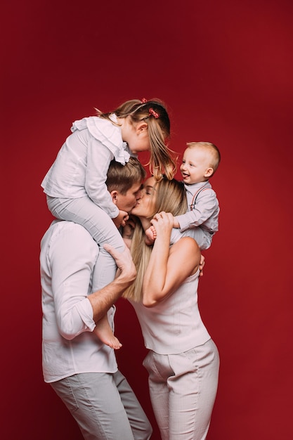 Marido e mulher beijando com filhos nos ombros.