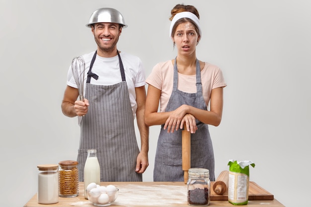 Marido e mulher posam na cozinha preparando um jantar saboroso