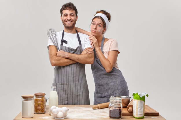 Marido e mulher posam na cozinha preparando um jantar saboroso