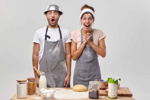 Marido e mulher posam na cozinha preparando um jantar saboroso