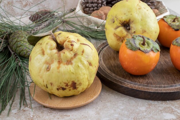 Marmelos e caquis orientais em arranjo decorativo sobre superfície de mármore.