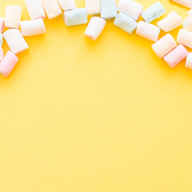 Marshmallows macios sobre a borda do fundo amarelo