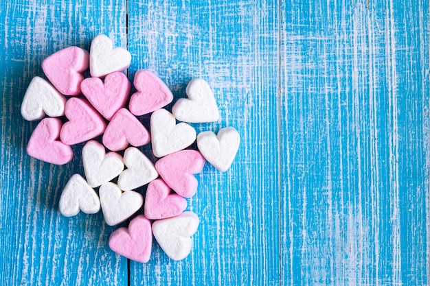 Marshmallows rosa e brancos em forma de coração na vista superior de fundo azul
