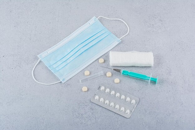 Máscara, ampola, seringa e comprimidos médicos em fundo de mármore. Foto de alta qualidade