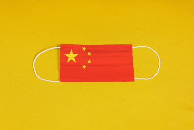 Máscara cirúrgica em fundo amarelo com bandeira da China