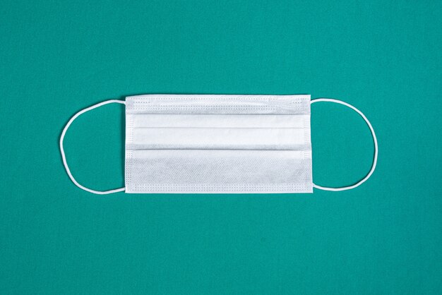 Máscara cirúrgica sobre fundo verde minimalista