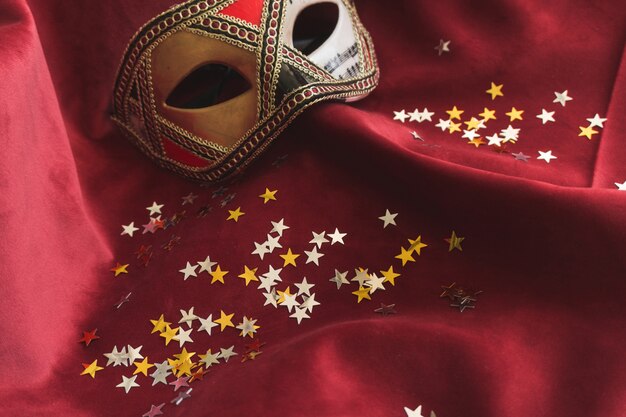 Máscara Venetian em uma tela vermelha com confetti estrela
