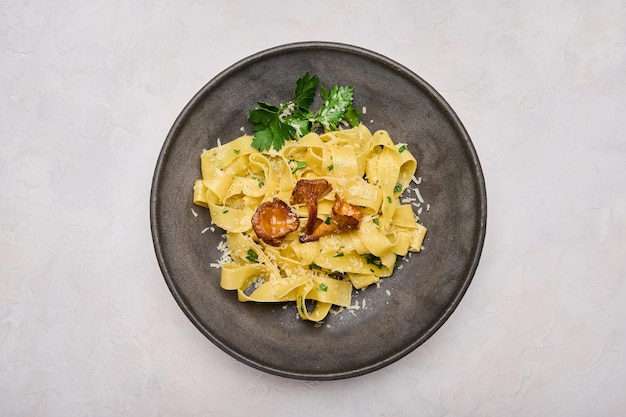 Massa caseira italiana pappardelle com cogumelos chanterelles, queijo e salsa no prato escuro