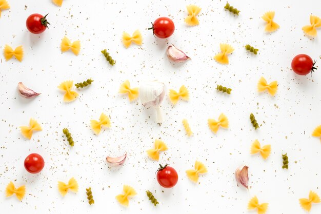 Massa de Fusilli e farfalle com ingrediente espalhado no fundo branco