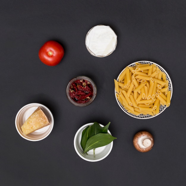 Massa de penne cru e ingrediente organizado no balcão da cozinha