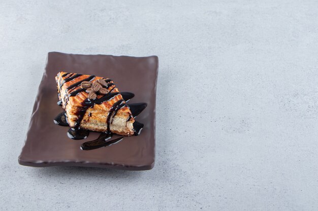 Massa doce decorada com chocolate colocada em prato escuro. Foto de alta qualidade