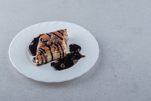 Massa doce decorada com xarope de chocolate colocado em prato branco. Foto de alta qualidade