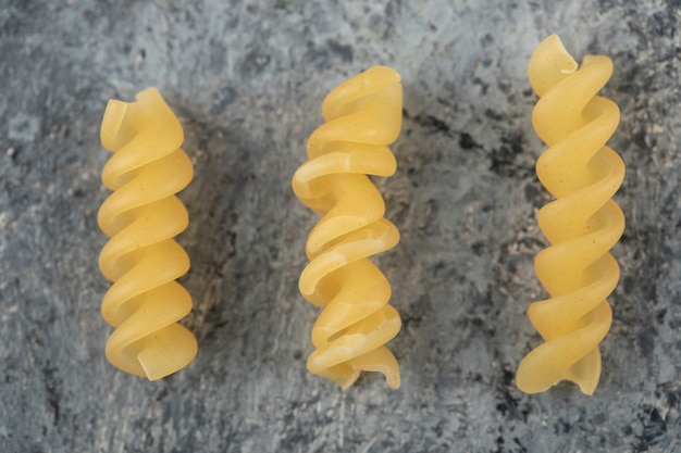 Foto grátis massa espirala fusilli seca crua sobre uma mesa de mármore.