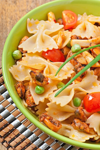 Foto grátis massa farfalle com frutos do mar, tomate cereja e ervilhas verdes