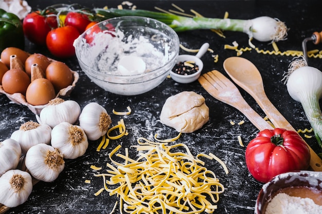 Massa perto de ingredientes variados na mesa da cozinha