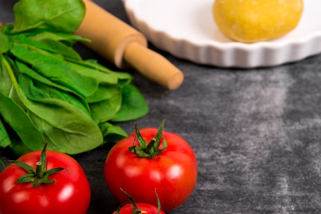 Massa, verduras e tomate na mesa de madeira cinza