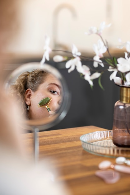 Massagem de rosto de mulher no espelho com gua sha