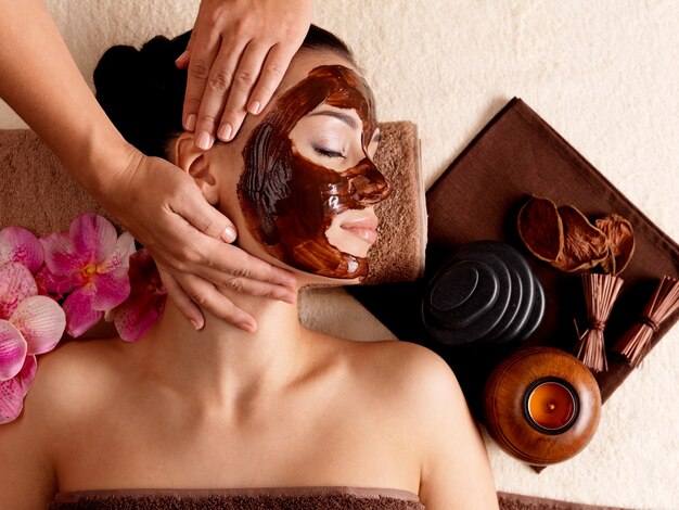 Massagem de spa para jovem com máscara facial no rosto - dentro de casa