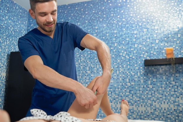 Massagista fazendo massagem anticelulite em mulher deitada no sofá