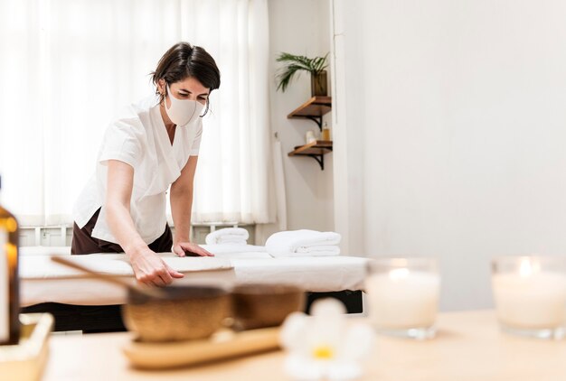 Massoterapeuta de spa com máscara facial trabalhando no novo normal