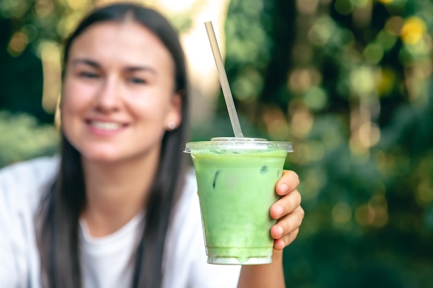 Foto grátis matcha latte gelado em um copo de plástico nas mãos de uma mulher