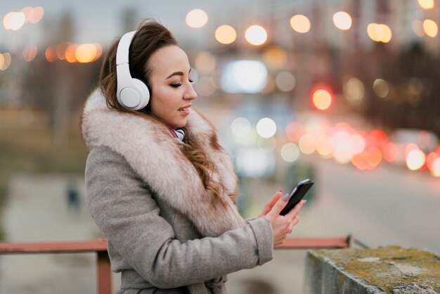 Meados de tiro mulher no telhado usando fones de ouvido