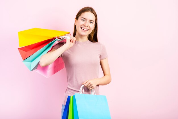 Meados de tiro mulher sorridente segurando sacos e olhando para a câmera