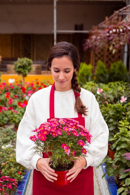 Foto grátis meados de tiro mulher vestida com roupas de jardinagem, segurando o vaso de flores