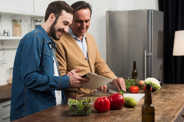 Foto grátis meados de tiro pai e filho fazendo salada na cozinha