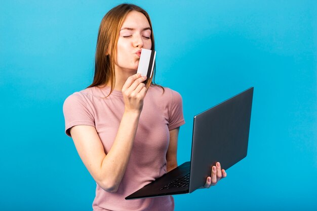 Meados tiro mulher segurando laptop e beijar cartão de crédito