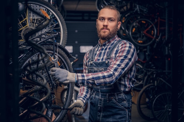 Foto grátis mecânico barbudo fazendo manual de serviço de roda de bicicleta em uma oficina.