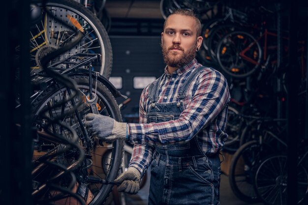 Mecânico barbudo fazendo manual de serviço de roda de bicicleta em uma oficina.