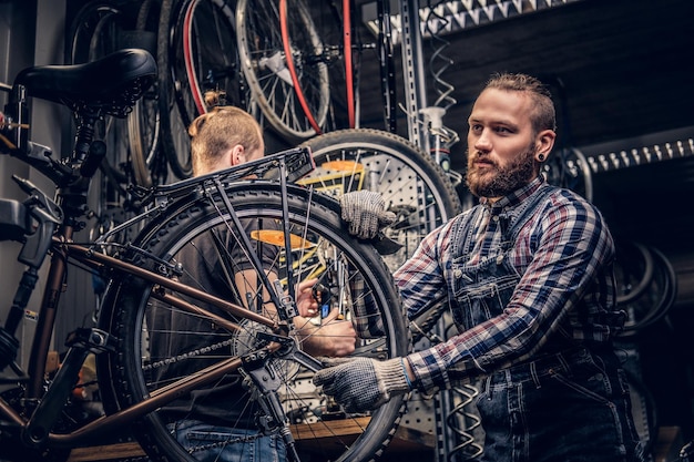 Mecânico barbudo fazendo manual de serviço de roda de bicicleta em uma oficina.