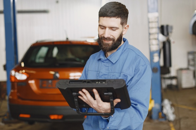 Foto grátis mecânico de automóveis com um tablet perto de um carro com roupa de trabalho
