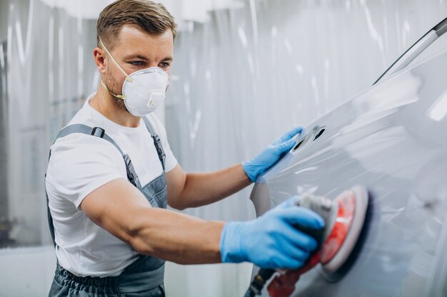 Mecânico de automóveis polindo carro antes de pintar