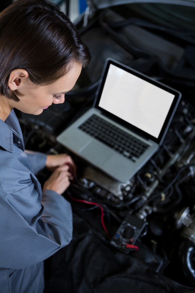 Foto grátis mecânico de motor de carro fêmea que examina com a ajuda de laptop